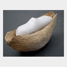 sculpture in carved wood with a carved form in blue gypsum stone sitting within the wood