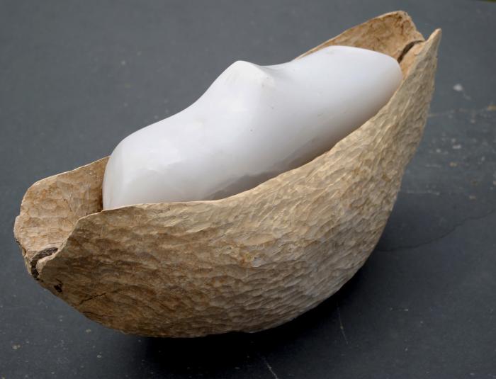 sculpture in carved wood with a carved form in blue gypsum stone sitting within the wood